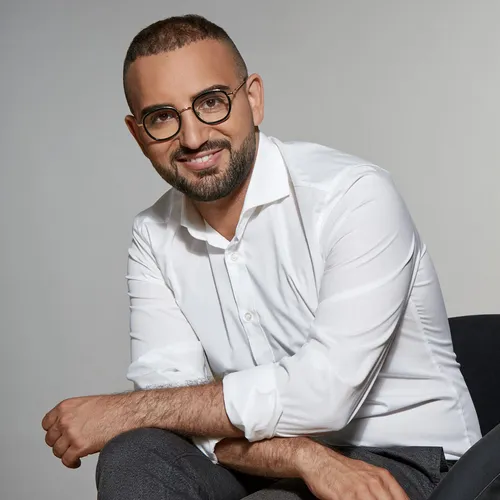Portrait von Kassem Taher Saleh im weißen Hemd, er lacht in die Kamera  
